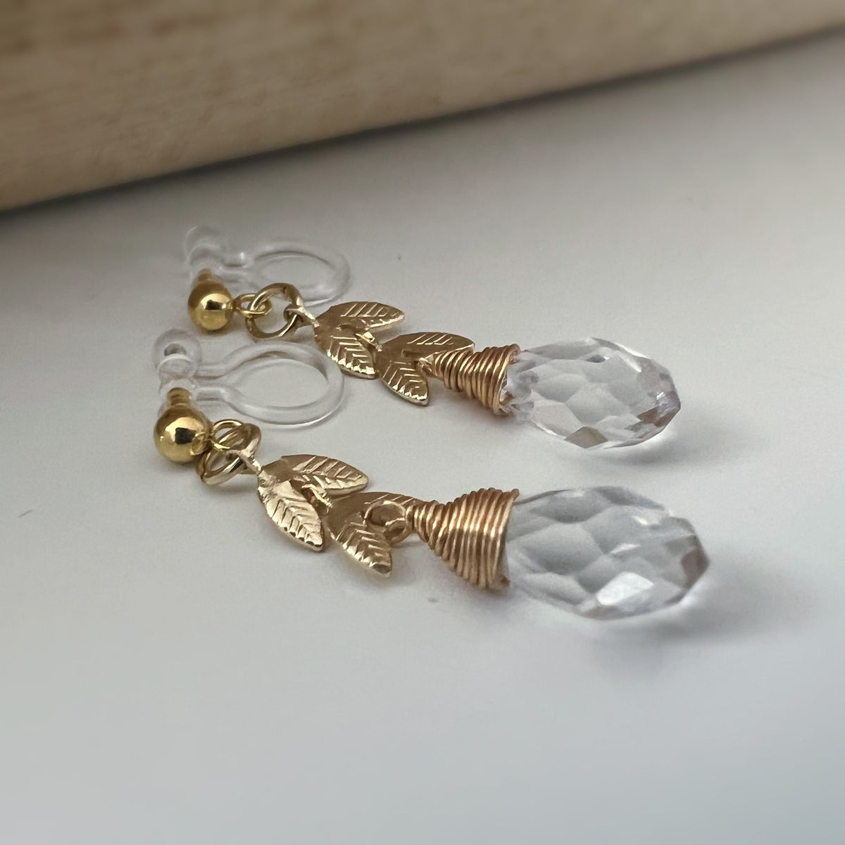 Gold leaf chain dangling ear clips with transparent faceted pearl in the shape of a drop of water Comfortable invisible clips.