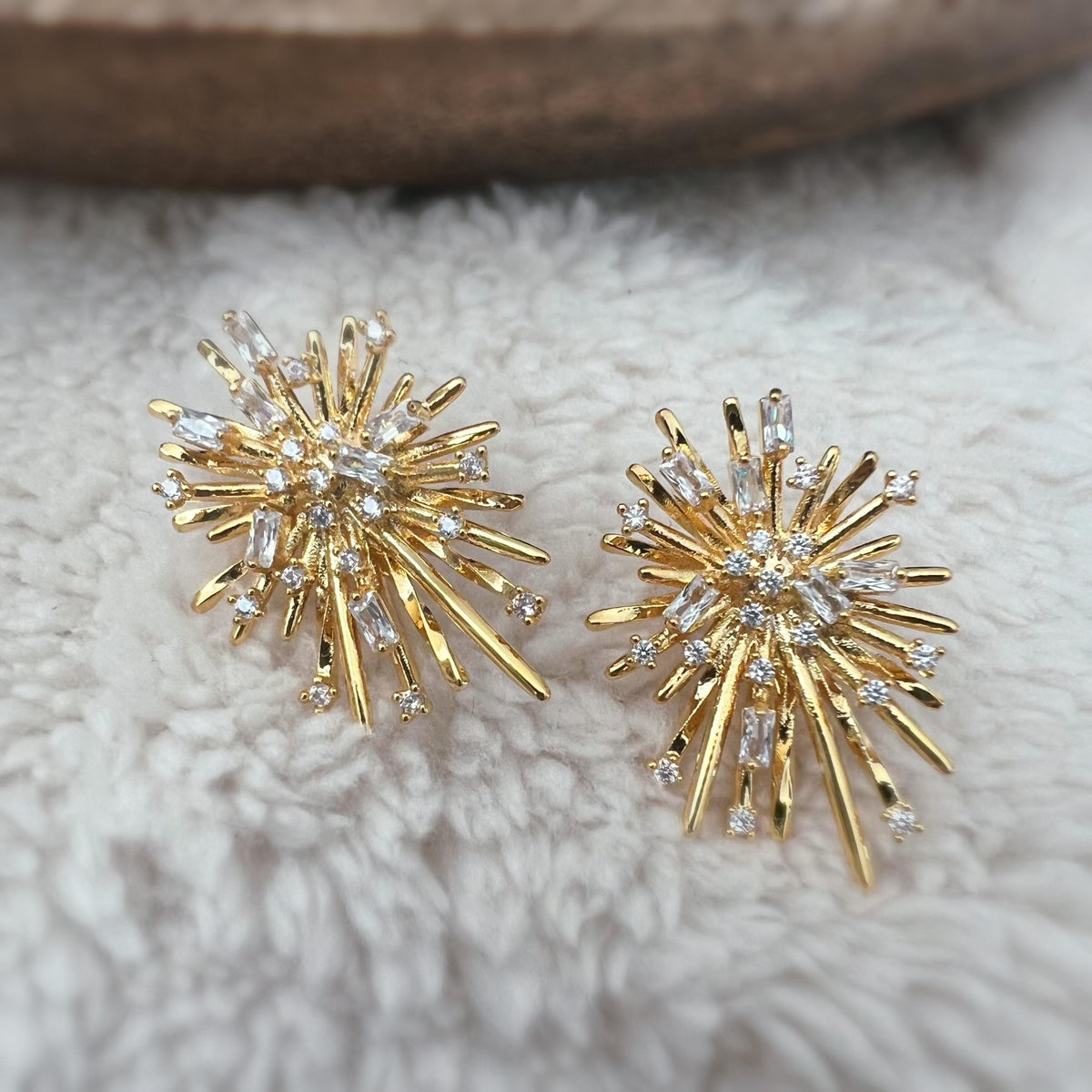 Clips d'oreilles dorés en forme de rayons lumineux, sertis de cristaux étincelants. Une touche glamour idéale pour sublimer vos tenues.