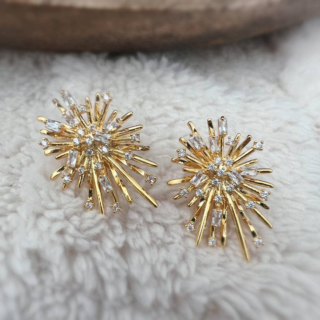 Clips d'oreilles dorés en forme de rayons lumineux, sertis de cristaux étincelants. Une touche glamour idéale pour sublimer vos tenues.