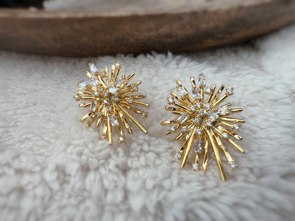 Clips d'oreilles dorés en forme de rayons lumineux, sertis de cristaux étincelants. Une touche glamour idéale pour sublimer vos tenues.