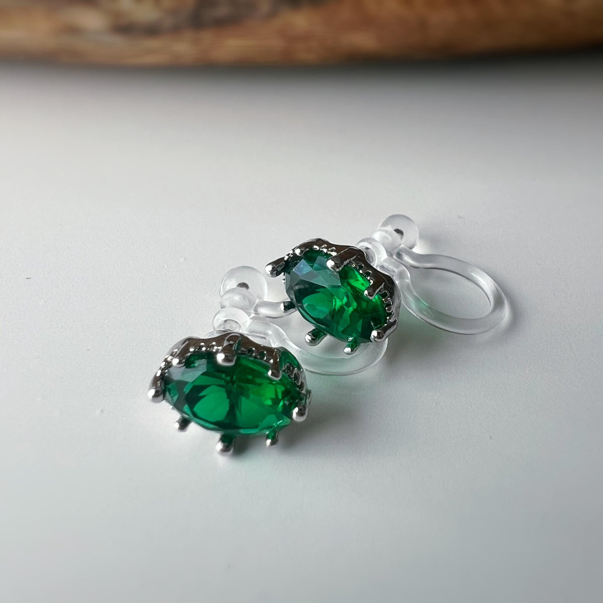 Boucles d'oreilles clips pierres vert émeraude scintillantes serties dans un cadre argenté raffiné Idéales pour une touche de sophistication
