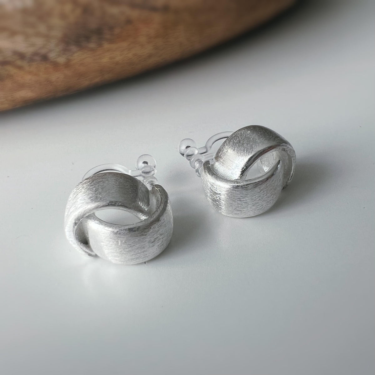 Boucles d'oreilles clip argent brossé au design torsadé élégant. Légères confortables grâce à leur clip transparent, oreilles non percées.
