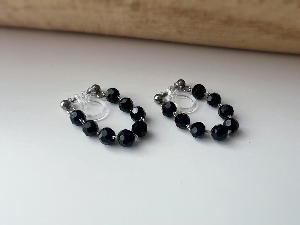 Boucles d'oreilles clips élégantes avec perles noires facettées en forme de cercle. Idéales pour un look raffiné et intemporel.