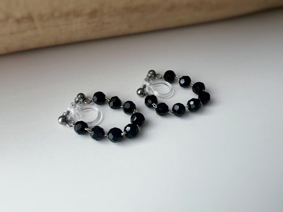Boucles d'oreilles clips élégantes avec perles noires facettées en forme de cercle. Idéales pour un look raffiné et intemporel.