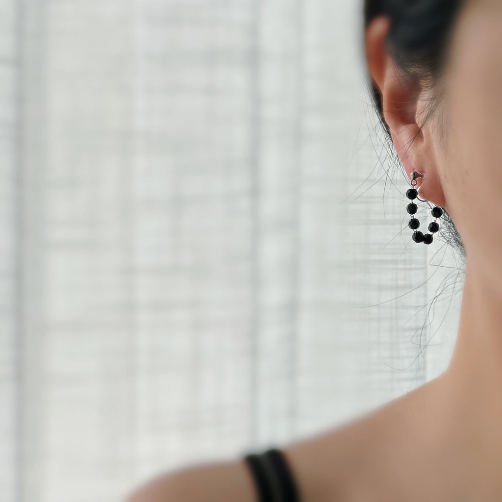 Boucles d'oreilles clips élégantes avec perles noires facettées en forme de cercle. Idéales pour un look raffiné et intemporel.