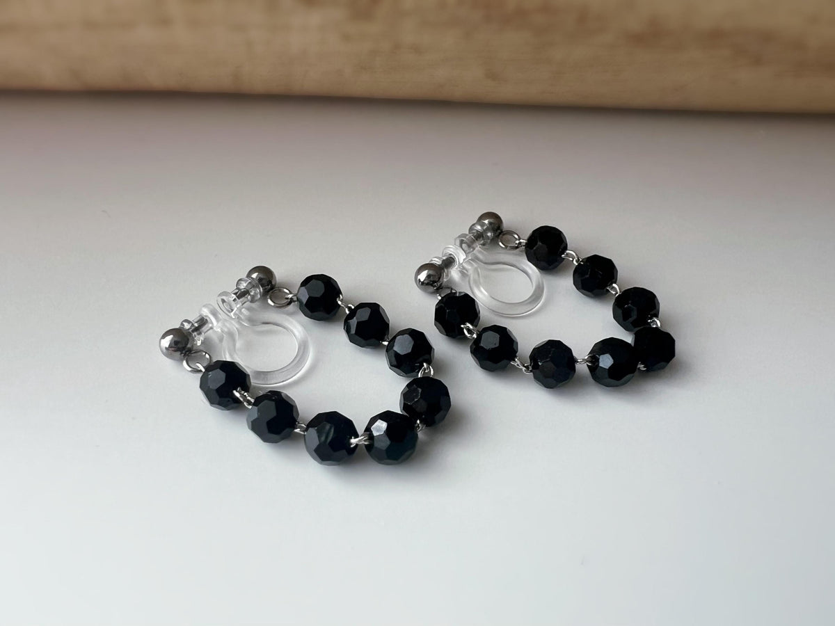 Boucles d'oreilles clips élégantes avec perles noires facettées en forme de cercle. Idéales pour un look raffiné et intemporel.