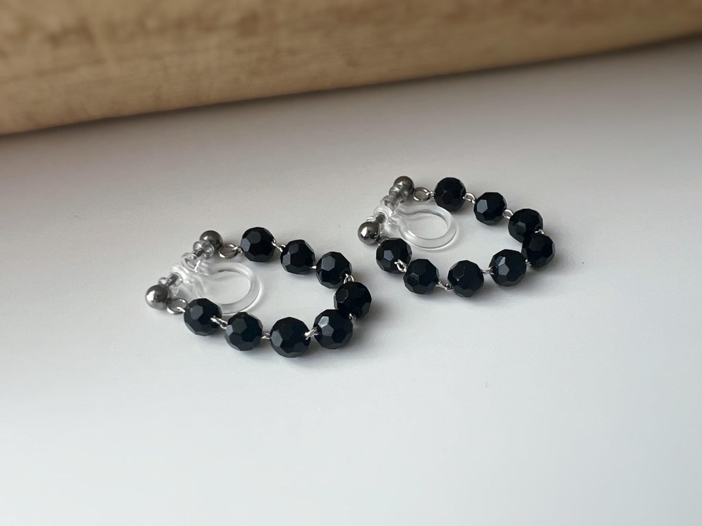 Boucles d'oreilles clips élégantes avec perles noires facettées en forme de cercle. Idéales pour un look raffiné et intemporel.