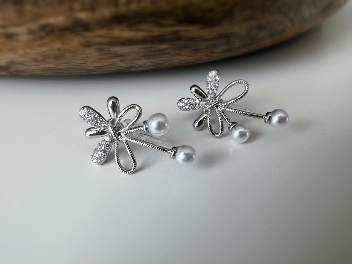 Boucles d’oreilles à clips fleurs strass, mini perles blanches couleur Or / Argent. Design raffiné pour un look délicat, sans perçage.