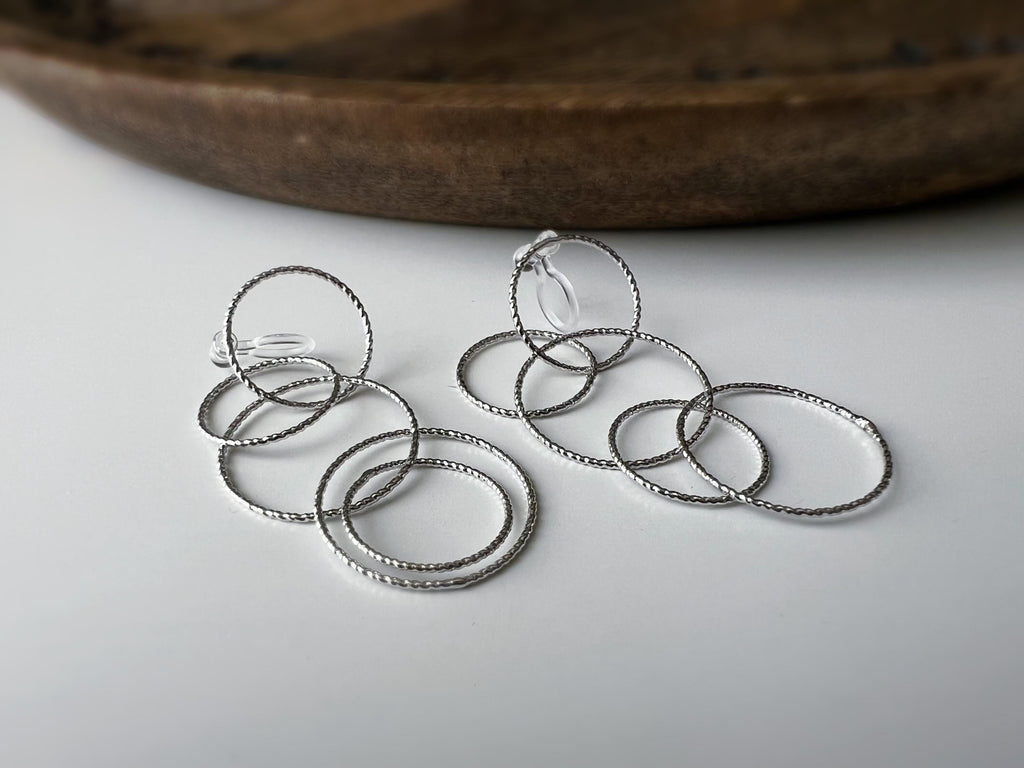 Boucles d'oreilles Clips, anneaux entrelacés argentés. Élégantes et légères, elles subliment vos looks avec une touche moderne et raffinée.