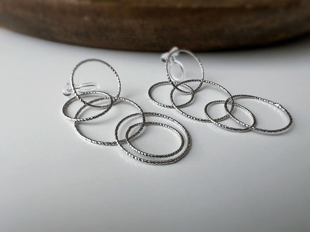 Boucles d'oreilles Clips, anneaux entrelacés argentés. Élégantes et légères, elles subliment vos looks avec une touche moderne et raffinée.